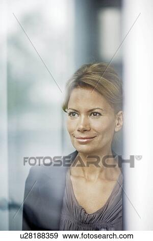 Woman looking through window, smiling View Large Photo Image Stock Photo - Woman looking through window, smiling. Fotosearch