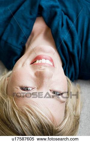 Stock Photography - Woman lying on sofa looking at viewer. Fotosearch