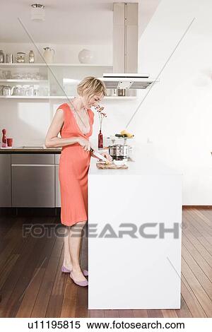 Stock Photography - Woman preparing food in a kitchen. Fotosearch