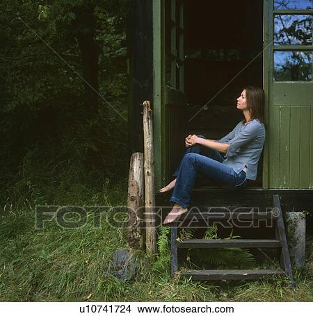 Picture - woman relaxing by summer house. Fotosearch