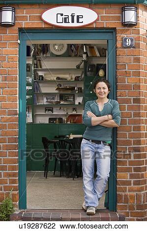 Stock Image - Woman standing in front of a cafe. Fotosearch