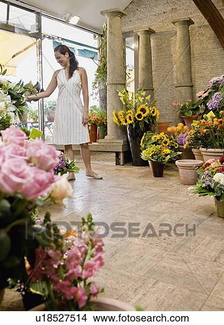Picture - Woman standing inside a flower shop. Fotosearch