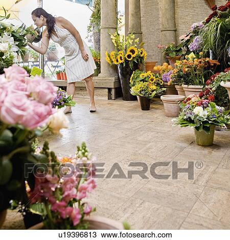 Stock Image - Woman standing inside a flower shop. Fotosearch