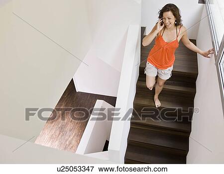 Stock Photo - Woman walking downstairs while on phone. Fotosearch