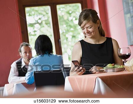 Woman working on phone while eating View Large Photo Image Stock Photo - Woman working on phone while eating. Fotosearch