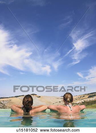 Stock Image - Women in pool admiring view. Fotosearch