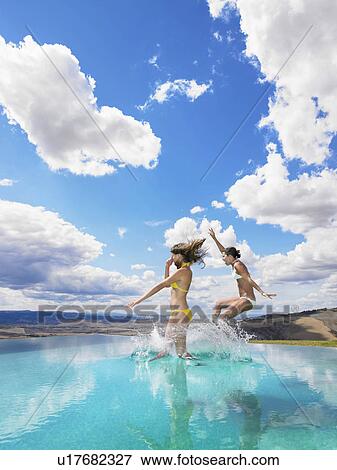 Stock Photo - Women jumping in swimming pool. Fotosearch