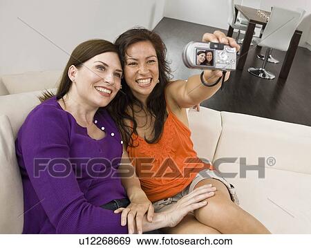 Stock Photo - Women on the couch taking self portrait. Fotosearch
