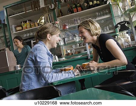 Stock Photo - Women talking over coffee at a cafe. Fotosearch