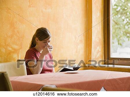 Women with a cup of coffee while reading View Large Photo Image Stock Photograph - Women with a cup of coffee while reading. Fotosearch