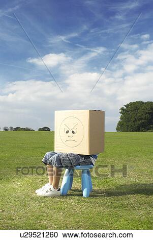 Stock Image - young boy on stool with box on head. Fotosearch