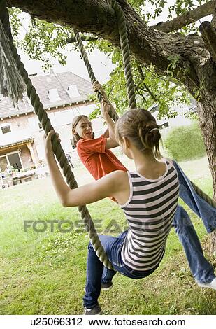 Stock Image - Young girl and boy on a tree swing. Fotosearch