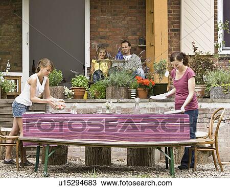 Stock Image - Young girl and woman setting the table. Fotosearch