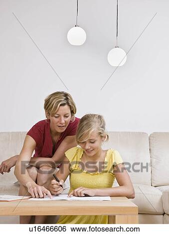 Stock Photograph - Young girl doing homework with woman. Fotosearch