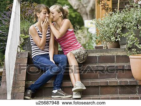 Stock Photo - Young girls telling each other secrets. Fotosearch