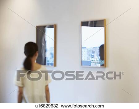 Stock Image - Mid-Adult Woman Walking by Wall Mirrors. Fotosearch