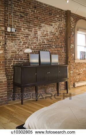 Stock Photography - Cabinet in bedroom against brick wall. Fotosearch