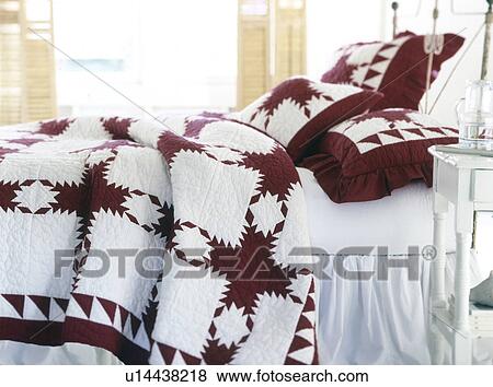 Stock Photo - Detail bed with red and white quilt. Fotosearch