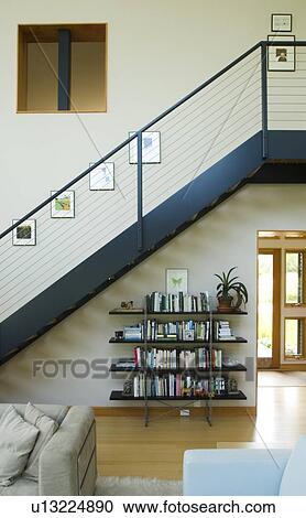 Stock Image - Modern staircase in home above bookcase. Fotosearch