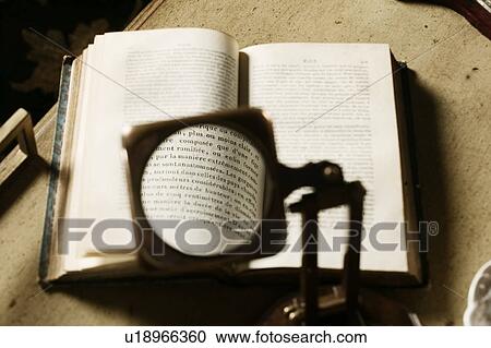 Stock Image - Reading magnifying glass above book. Fotosearch
