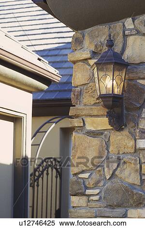 Stock Photography - Wall sconce on exterior stone wall. Fotosearch