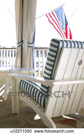 Stock Image - White Adirondack chair with striped cushions. Fotosearch