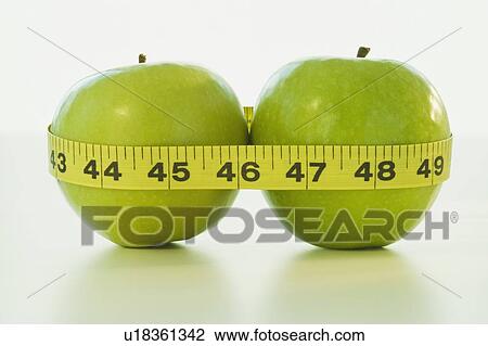 Stock Image - Apples wrapped in tape measure. Fotosearch
