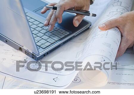 Architect with blueprints and laptop View Large Photo Image Stock Image - Architect with blueprints and laptop. Fotosearch