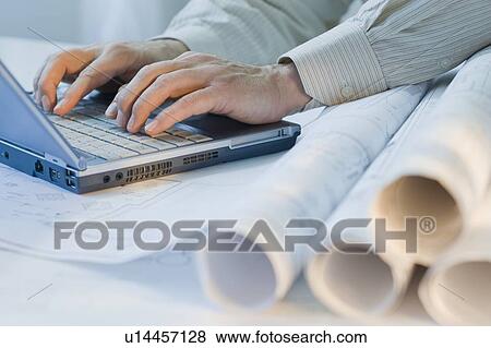Architect with blueprints and laptop View Large Photo Image Stock Photo - Architect with blueprints and laptop. Fotosearch