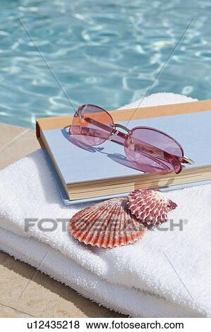 Book and sunglasses by swimming pool View Large Photo Image Stock Photo - Book and sunglasses by swimming pool. Fotosearch