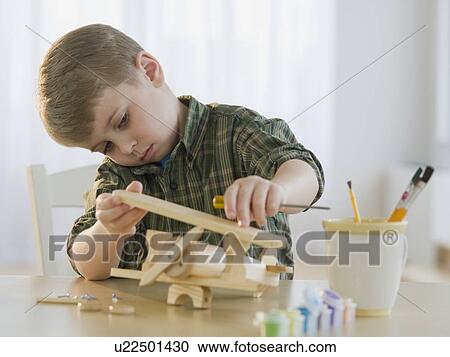 Stock Image - Boy building wooden airplane model. Fotosearch