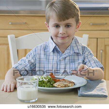 Stock Photography - Boy eating dinner. Fotosearch