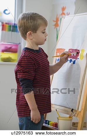 Boy painting on easel View Large Photo Image Stock Image - Boy painting on easel. Fotosearch