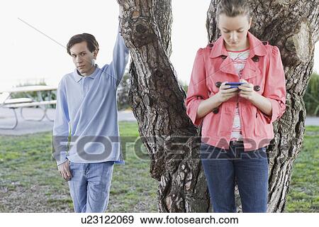Boy watching girl text messaging outdoors View Large Photo Image Stock Photo - Boy watching girl text messaging outdoors. Fotosearch