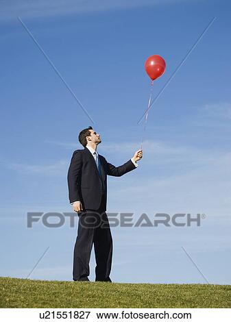 Businessman holding red balloon View Large Photo Image Stock Photo - Businessman holding red balloon. Fotosearch