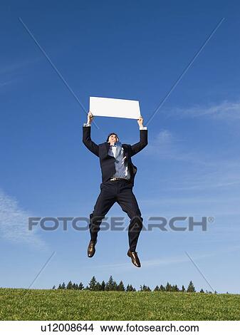 Businessman jumping with blank sign View Large Photo Image Picture - Businessman jumping with blank sign. Fotosearch