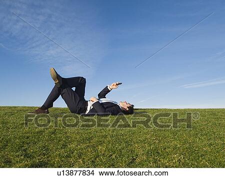 Picture - Businessman laying in grass. Fotosearch