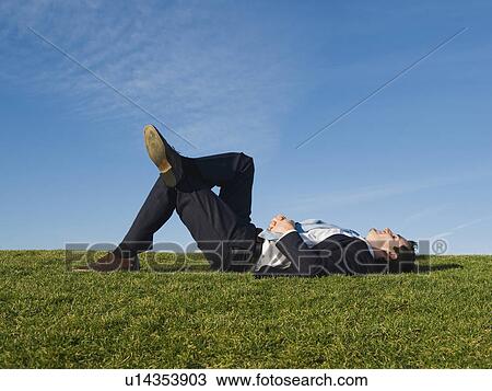 Stock Image - Businessman laying in grass. Fotosearch