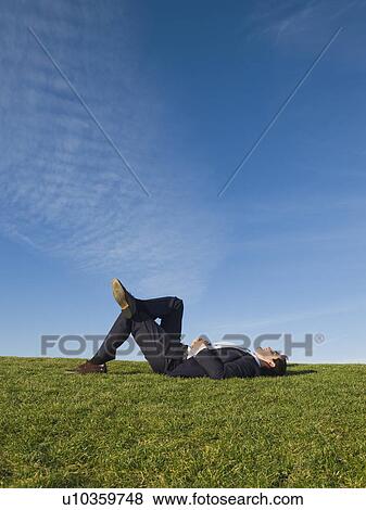 Stock Photo - Businessman laying in grass. Fotosearch