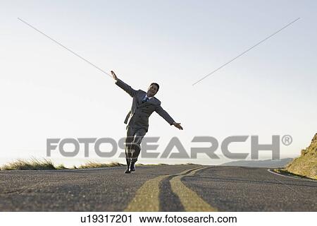 Stock Image - Businessman running on remote road. Fotosearch