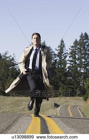Stock Photo - Businessman running on remote road. Fotosearch