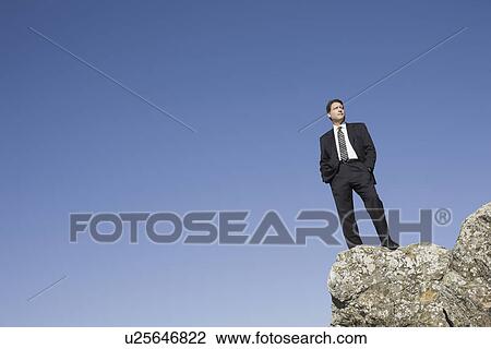 Businessman standing on edge of cliff View Large Photo Image Stock Image - Businessman standing on edge of cliff. Fotosearch