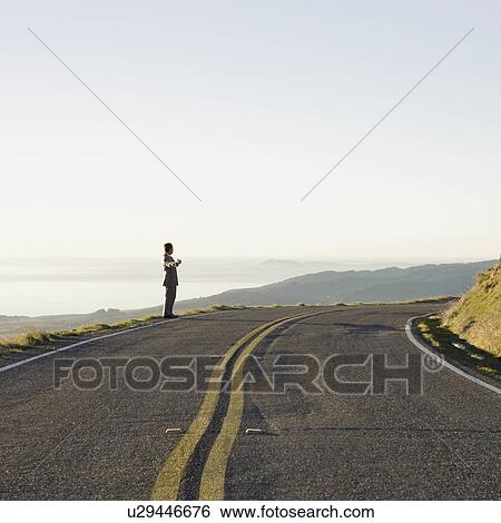 Businessman standing on remote road View Large Photo Image Stock Photograph - Businessman standing on remote road. Fotosearch