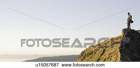 Businessman standing on rock overlooking ocean View Large Photo Image Stock Photo - Businessman standing on rock overlooking ocean. Fotosearch