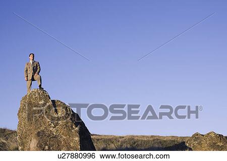 Stock Photograph - Businessman standing on rock. Fotosearch