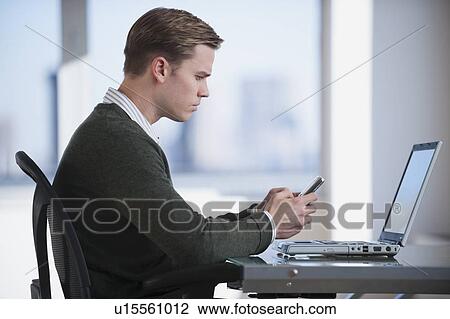 Businessman text messaging in office View Large Photo Image Stock Image - Businessman text messaging in office. Fotosearch