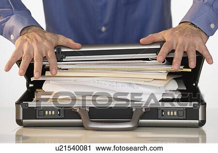 Stock Image - Businessman trying to close briefcase. Fotosearch