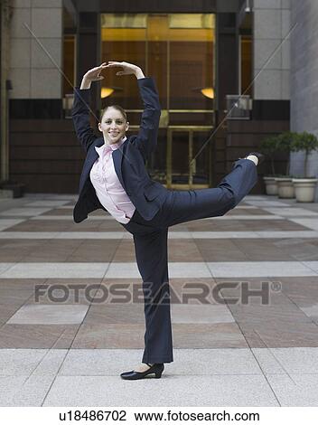 Stock Image - Businesswoman dancing in urban setting. Fotosearch
