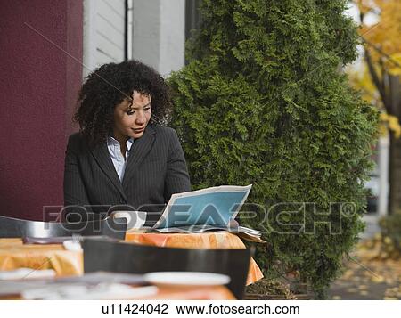 Stock Image - Businesswoman sitting at outdoor cafe. Fotosearch