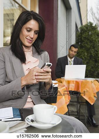 Businesswomen text messaging at outdoor cafe View Large Photo Image Stock Photograph - Businesswomen text messaging at outdoor cafe. Fotosearch